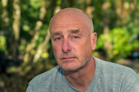 Portrait, man, camera view, sad, beard, unshaven, bald, background blurred, edge of forest,