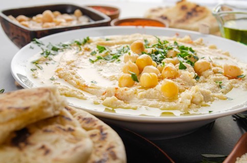 Closeup view at Hummus topped with beans olive oil and green coriander leaves on kitchen table with