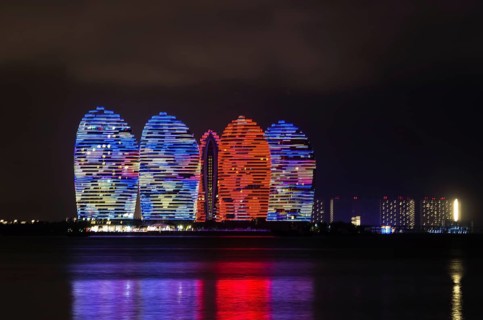 Scenic night view of buldings on Phoenix island with backlight and reflection in a sea in Sanya,