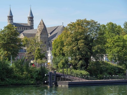Large church near a river, surrounded by trees in a historic city, maastricht. netherlands