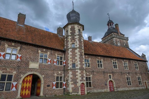 Medieval castle with red tiled roofs and towers under a cloudy sky, Raesfeld, North