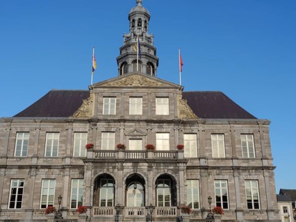 A historic building with a stone façade and several windows standing against the blue sky,