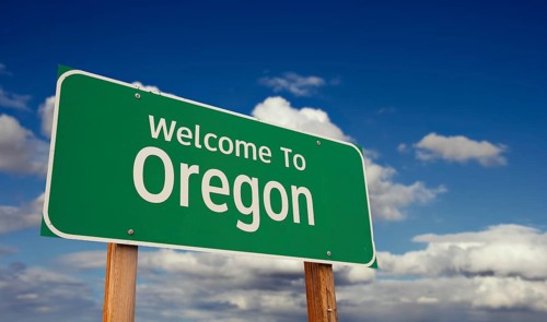 Welcome to oregon green road sign over blue sky with some clouds