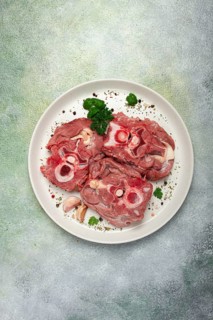 Raw steak, calf's neck on the bone, fresh meat, on a white plate, top view, no people