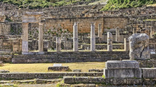 Ancient columns and ruins of a historical site surrounded by vegetation and stone structures in the