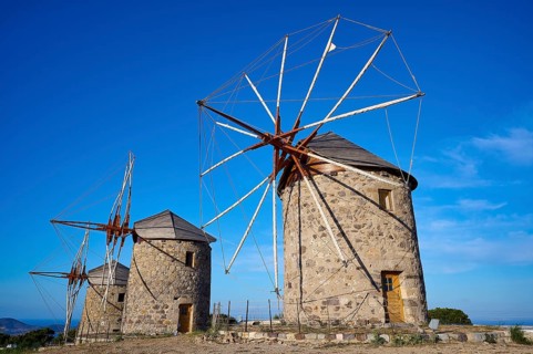 Two old windmills under a clear blue sky and a natural landscape, windmills, on a ridge, above