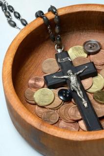 Crucifix with coins and buttons in a wooden bowl, church and money