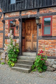 Hollyhocks (Alcea rosea) at a door tin a half-timbered house in a small street in the idyllic