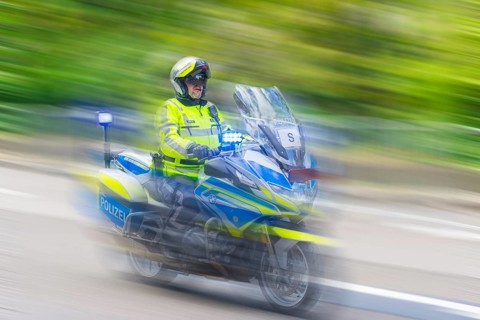 Policeman on a motorbike driving fast along the road, the speed is emphasised by the motion blur,