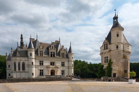 Castle with large tower on gravel square and cloudy sky in the background, Chenonceau Castle,