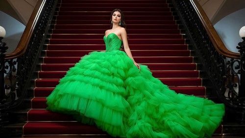 Young woman in a stunning green ball gown cascading dress at a red staircase, AI generated