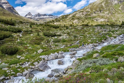 Mountaineer on a bridge over a mountain stream, Hornkeesbach, in front of a picturesque mountain