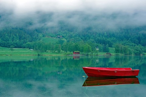 A small, red boat on a calm lake, idyll, surrounded by fog and green nature, Stryn, Mindesundet,