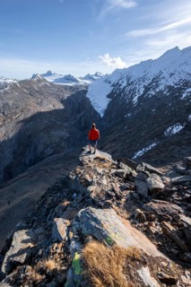 Mountaineer standing on a rock, surrounded by an impressive mountain landscape with snow-covered