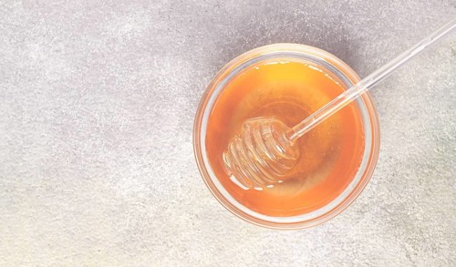 Spoon with honey, on the table, spindle for honey, close-up, rustic view