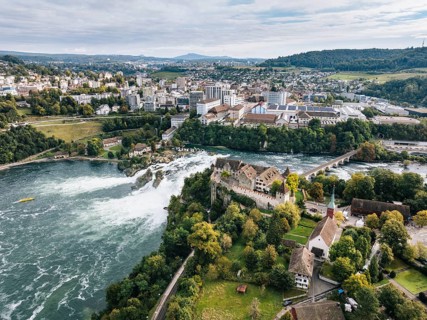 Aerial view of the Rhine Falls with Laufen Castle with autumnal vegetation, on the horizon the town