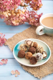 Chocolate truffle candies with cup of coffee on a blue wooden background and linen textile. side