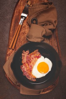 Fried egg with bacon, in a cast-iron pan, breakfast, top view, close-up, homemade, no people