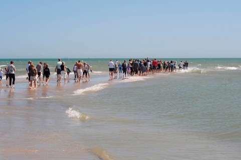 Ttourists standing at the northern tip of Denmark where the Baltic Sea and North Sea meet at Skagen
