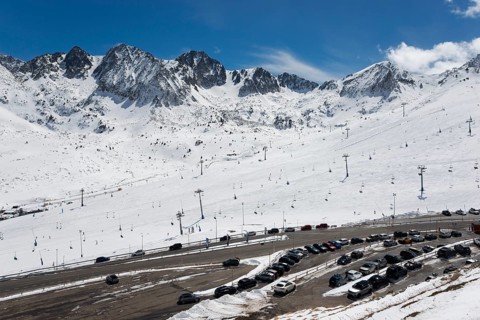 Schneebedecktes Skigebiet in den Bergen mit Skiliften und Autos auf dem Parkplatz unter einem