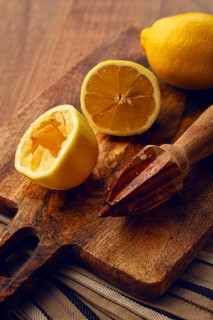 Lemons and a wooden manual citrus juicer, on a chopping board, close-up, no people