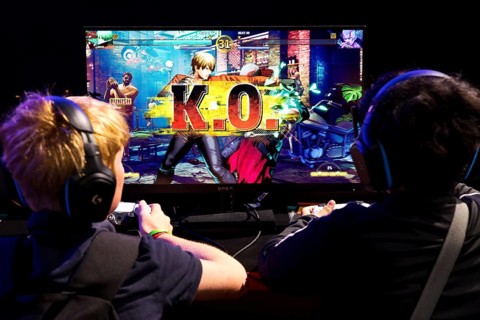 Two young visitors in front of a screen with a computer game, Gamescom trade fair, the world's