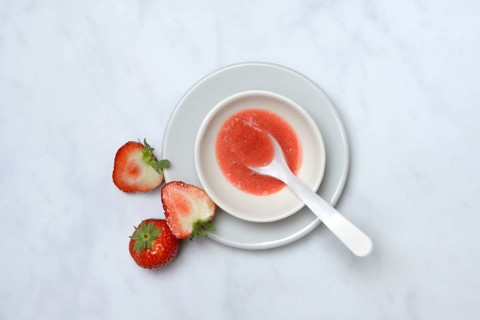 Strawberry sauce in small bowls and strawberries, strawberry coulis