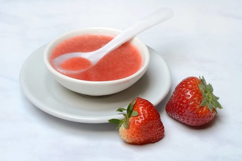 Strawberry sauce in small bowls and strawberries, strawberry coulis