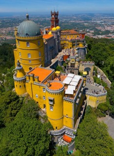 Historic castle in yellow on a hill with an impressive view and surrounded by forest, aerial view,