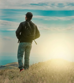 Rear view of backpacker man walking in the mountain. Low angle of backpacker man walking in the