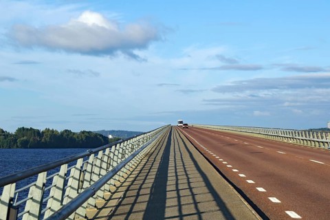 Long bridge over water with blue sky and few clouds, shadow on road, Storsjon, Fröson Bridge,
