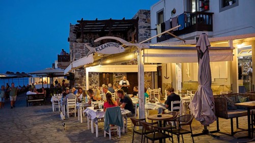 A restaurant on the street where people eat and chat by candlelight at dusk, Mandraki, Nisyros,