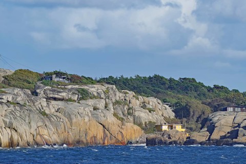 Coastal landscape with rocks, a house and wooded background under a cloudy sky, Archipelago,