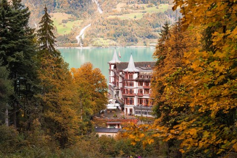A building on the lake, framed by autumnal trees and mountains, Lake Brienz, Switzerland, Europe