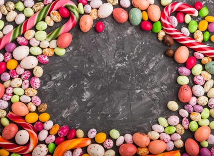 Colorful frame of multicolored candies on a black concrete background. Christmas cane, chocolate