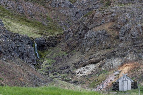 Old hut with stone walls and grass roof, waterfall, Laugar, Westfjords, Iceland, Europe
