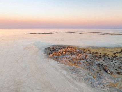 Rocky island with baobab trees in a dry salt pan, at sunset, aerial view, Kubu Island, Botswana,