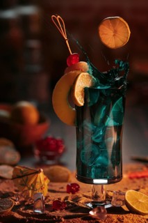 Sparkling cocktail in a glass with ice cube cubes, decorated with lime slices and cherries on a