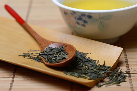 Green Sencha tea in tea bowl and tea leaves in wooden spoon, green tea, Japan, Asia
