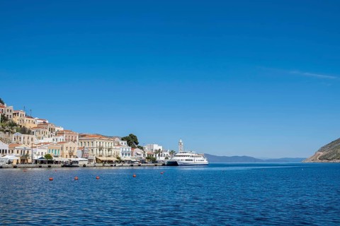 A picturesque coastal town with white houses and a boat in the clear blue sea under a bright blue