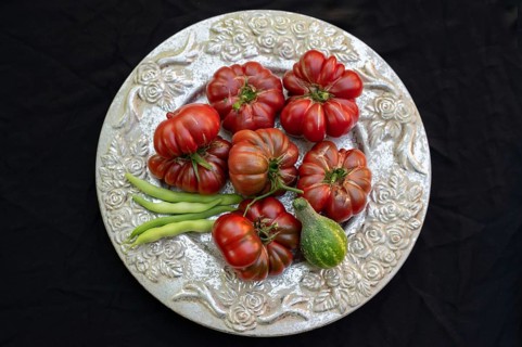 Tomatoes, ox hearts and a Vorgebirgstrauben pickled cucumber on a decorative plate on a black