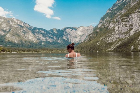 Woman standing in clear water with mountain landscape in the background, Soca Valley, Slovenia,