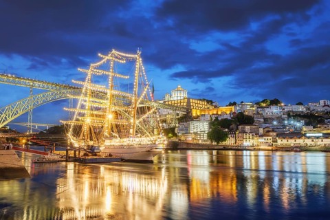 View of Vila Nova de Gaia city with a sailing ship and Dom Luis I bridge over Douro river in the