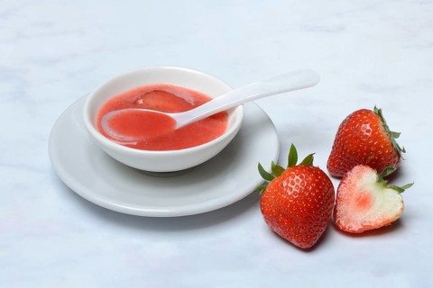 Strawberry sauce in small bowls and strawberries, strawberry coulis