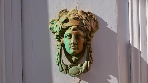 An antique bronze door knocker in the shape of a head, decorative and classically designed, Chora,