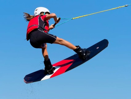 Boy or girl, jump over jump with wakeboard, red life jacket and water sports, water skiing in the