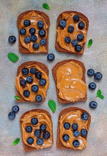 Rye bread with peanut paste and fresh blueberries, top view, no people
