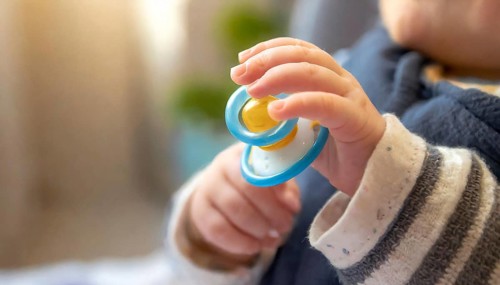 A baby's hand holds a blue dummy in close-up, conveys care and security, AI generated, AI generated