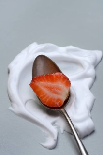 Strawberry with cream on a spoon
