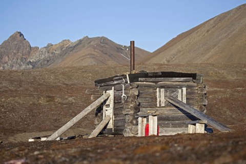 Wooden hunting log cabin tightly shut with logs against raiding polar bears on Svalbard,